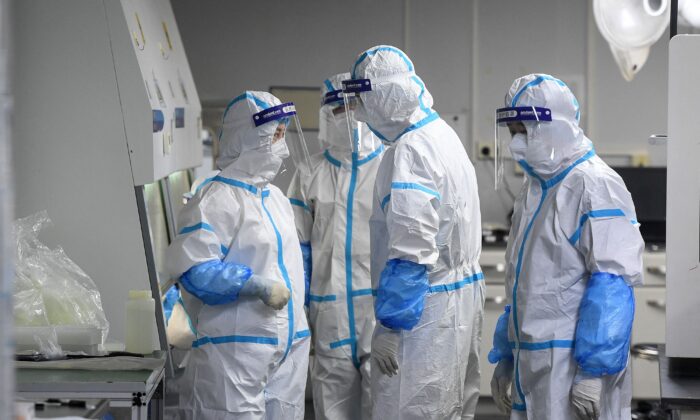 Các kỹ thuật viên phòng thí nghiệm đeo thiết bị bảo vệ cá nhân đang làm việc trên các mẫu bệnh phẩm tầm soát virus COVID-19 tại Phòng thí nghiệm Hỏa Nhãn, một cơ sở xét nghiệm COVID-19, tại Vũ Hán ở tỉnh Hồ Bắc, miền trung Trung Quốc, vào ngày 04/08/2021. (Ảnh: STR/AFP qua Getty Images)