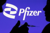Một người cầm ống chích tạo dáng trước logo Pfizer Inc. vào ngày 11/12/2021. (Ảnh: Dado Ruvic/Reuters)