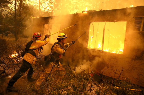 Lính cứu hỏa cố gắng ngăn ngọn lửa từ một ngôi nhà đang cháy lan sang khu chung cư lân cận khi họ tiến hành dập tắt đám cháy Camp Fire ở Paradise, California, ngày 09/11/2018. (Ảnh: Justin Sullivan/Getty Images)