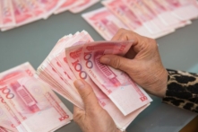 Một người phụ nữ đếm các tờ tiền nhân dân tệ của Trung Quốc ở Vancouver, Canada, ngày 27/10/2015. (Ảnh: Benjamin Chasteen/The Epoch Times)