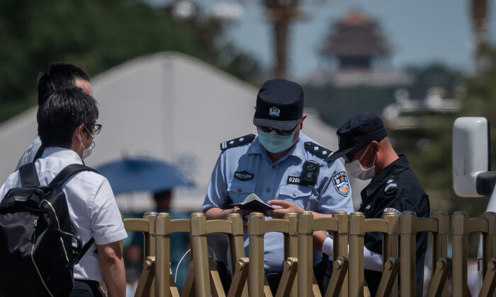 Công an (phải) kiểm tra sổ thông hành của một người ngoại quốc (trái) tại cổng an ninh ở lối vào Quảng trường Thiên An Môn tại Bắc Kinh vào ngày 04/06/2020. (Ảnh: NICOLAS ASFOURI/AFP qua Getty Images)