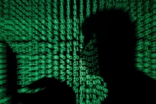 Chiếc bóng của một người đang cầm máy điện toán xách tay trên nền là hình ảnh mã mạng trong bức ảnh minh họa chụp ngày 13/05/2017. (Ảnh: Kacper Pempel/Reuters)