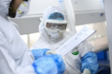 Các kỹ thuật viên phòng thí nghiệm trao đổi khi làm việc trên các mẫu xét nghiệm COVID-19 tại phòng thí nghiệm BGI ở Vũ Hán, Trung Quốc, vào ngày 06/02/2020. (Ảnh: STR/AFP qua Getty Images)
