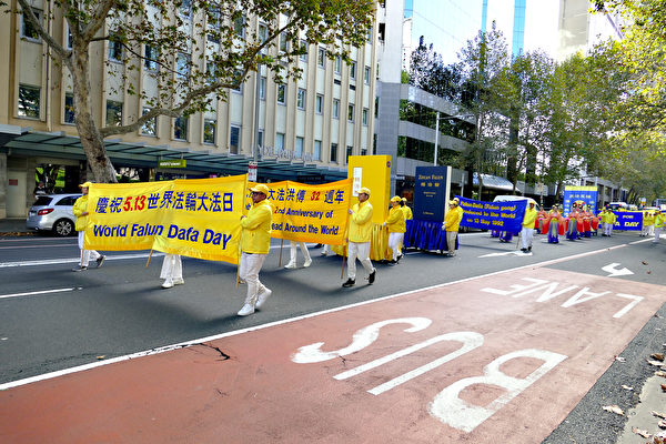 Các học viên Pháp Luân Công giương biểu ngữ chúc mừng Ngày Pháp Luân Đại Pháp Thế giới trong đoàn diễn hành, ở thành phố Sydney hôm 06/05/2024. (Ảnh: An Bình Nhã/The Epoch Times)