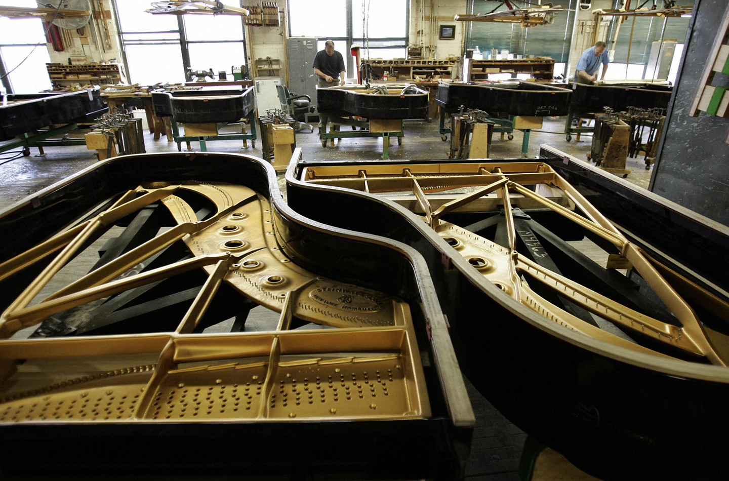 Các kỹ thuật viên tại nhà máy Steinway & Sons ở Thành phố Long Island, New York, đặt bảng cộng hưởng vào những chiếc đại dương cầm. (Ảnh: Timothy A. Clary/Getty Images)
