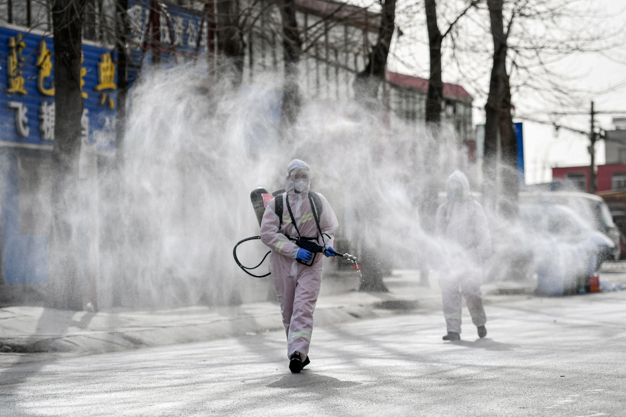 Người dân mặc đồ bảo hộ phun thuốc khử trùng trên một con phố ở Thạch Gia Trang, nơi được tuyên bố là khu vực có nguy cơ cao về COVID-19, ở tỉnh Hà Bắc, phía bắc Trung Quốc, vào ngày 15/01/2021. (Ảnh: Fabrice Coffrini/AFP qua Getty Images, STR/CNS/AFP qua Getty Images)