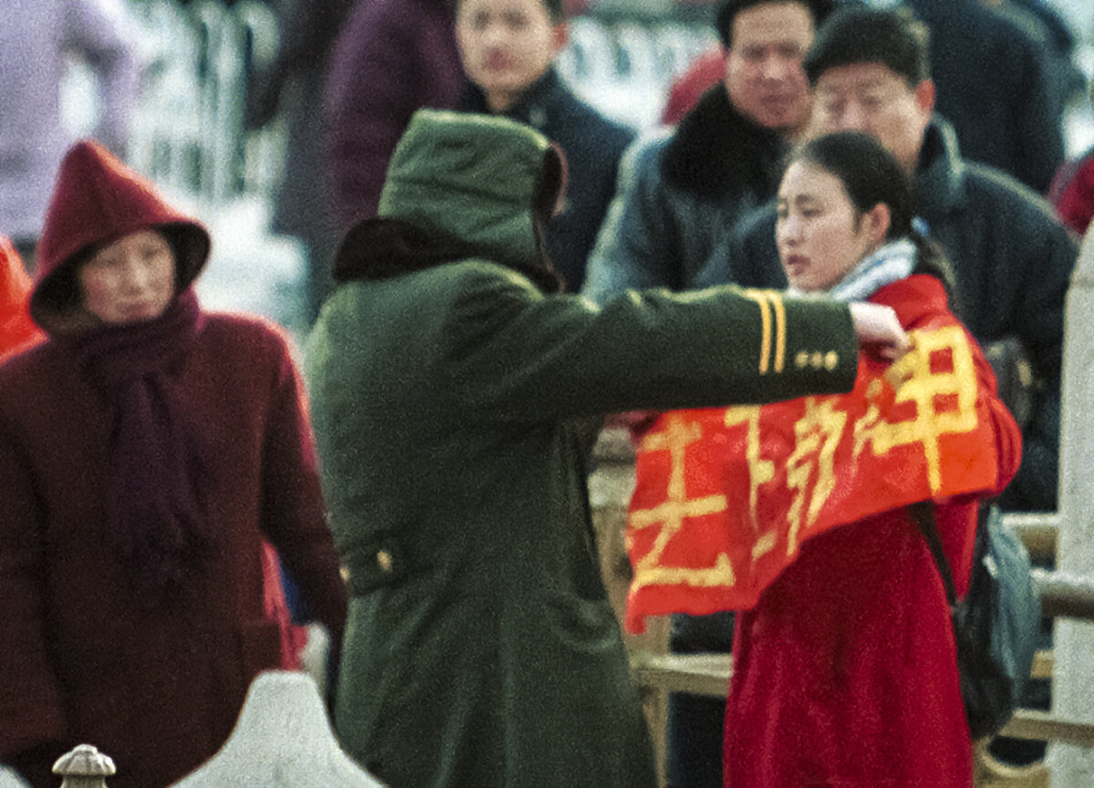 Một người phụ nữ giơ cao biểu ngữ Pháp Luân Công bị công an bắt giữ tại Cổng Thiên An Môn, Bắc Kinh, Trung Quốc, vào ngày 25/01/2001. (Ảnh: AP Photo/Greg Baker)