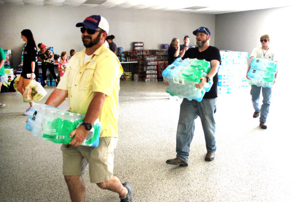 Các tình nguyện viên mang các thùng nước đóng chai vào Trung tâm Cộng đồng Valley View, Texas hôm 16/05/2024. (Ảnh: Michael Clements/The Epoch Times)