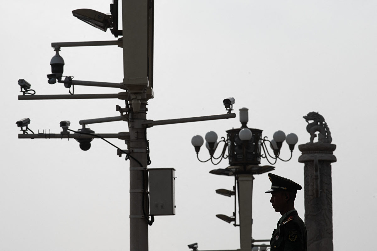 Ảnh chụp một cảnh sát vũ trang đứng gác trước máy quay giám sát tại Quảng trường Thiên An Môn, Bắc Kinh. (Ảnh: STR/AFP)