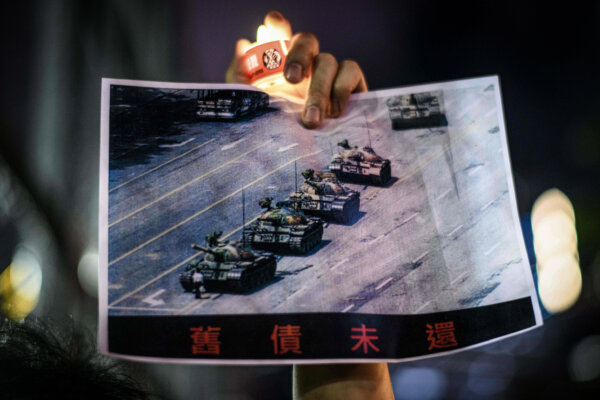 Trong lễ tưởng niệm vụ Thảm sát Thiên An Môn năm 1989, tại Công viên Victoria ở Hồng Kông vào ngày 04/06/2020, một người cầm tấm bích chương in bức ảnh chụp “Người chặn Xe tăng” (Tank Man) nổi tiếng đứng trước đầu xe tăng quân sự Trung Quốc tại Quảng trường Thiên An Môn ở Bắc Kinh vào ngày 05/06/1989. (Ảnh: Anthony Wallace/AFP qua Getty Images)