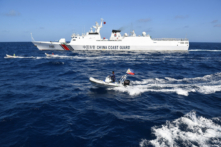 Một tàu Hải cảnh Trung Quốc (ở phía xa) tiến gần một cách nguy hiểm đến ngư dân Philippines trên hai chiếc thuyền gỗ (ở giữa), trong lúc một chiếc thuyền bơm hơi của Cơ quan Đánh cá và Nguồn lợi Thủy sản Philippines đang quan sát, gần Bãi cạn Scarborough, ở Biển Đông, hôm 16/02/2024. (Ảnh: Ted Aljibe/AFP/Getty Images)