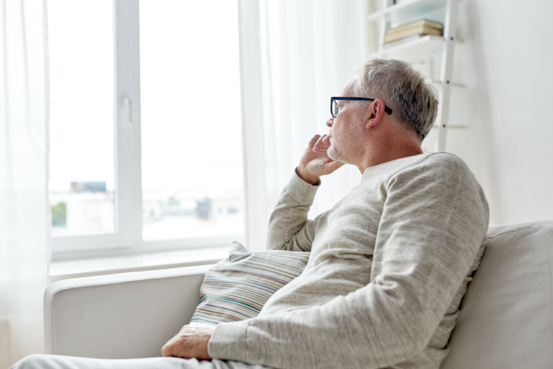 Một người đàn ông cao niên đang nhìn ra ngoài cửa sổ. (Ảnh: Ground Picture/Shutterstock)