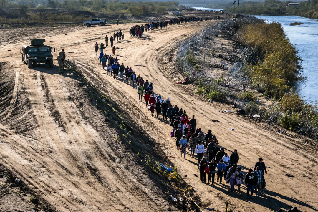 Một đoàn hơn 1,000 người nhập cư bất hợp pháp đi về phía trung tâm giải quyết tại chỗ của Lực lượng Tuần tra Biên giới Hoa Kỳ sau khi họ vượt qua Rio Grande từ Mexico vào Eagle Pass, Texas, vào ngày 18/12/2023. (Ảnh: John Moore/Getty Images)