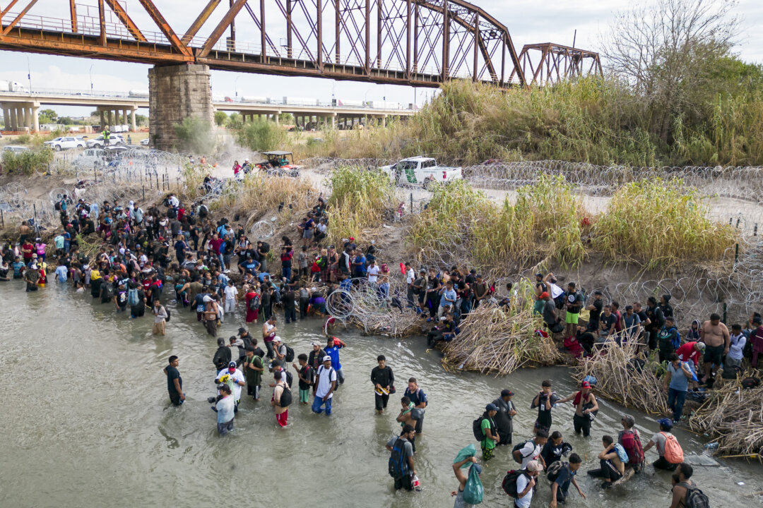 Những người nhập cư bất hợp pháp chờ đợi hàng rào dây thép gai mở ra ở Rio Grande để vào Hoa Kỳ, tại Eagle Pass, Texas, hôm 25/09/2023. (Ảnh: Andrew Caballero-Reynolds/AFP qua Getty Images)