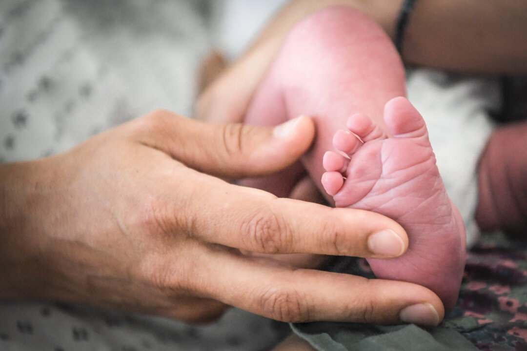 Một người phụ nữ ôm chân em bé trong một bức ảnh tư liệu. (Ảnh: Loic Venance/AFP qua Getty Images)