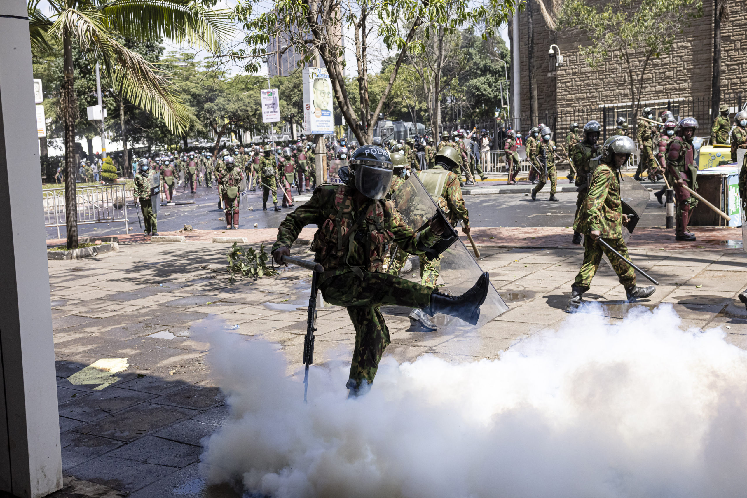 Một viên cảnh sát Kenya trong trang phục chống bạo động đá vào bình đựng hơi cay tại một cuộc biểu tình phản đối dự luật tài chính ở Nairobi, Kenya, hôm 25/06/2024. (Ảnh: Patrick Meinhardt/Getty Images)
