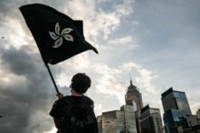 Một người đàn ông vẫy cờ Hồng Kông màu đen trên một con đường bên ngoài Khu liên hợp Hội đồng Lập pháp ở Hồng Kông vào ngày 01/07/2019. (Ảnh: Anthony Kwan/Getty Images)