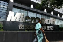 Nhân viên dọn dẹp vệ sinh đi ngang qua biển hiệu Microsoft bên ngoài một tòa nhà văn phòng Microsoft ở Bắc Kinh, vào ngày 31/07/2014. (Ảnh: Greg Baker/AFP/Getty Images)