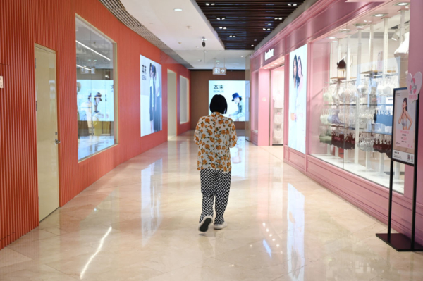 Một người phụ nữ đi ngang qua các cửa hàng trong một trung tâm mua sắm ở Bắc Kinh hôm 18/07/2023. (Ảnh: Greg Baker/AFP qua Getty Images)