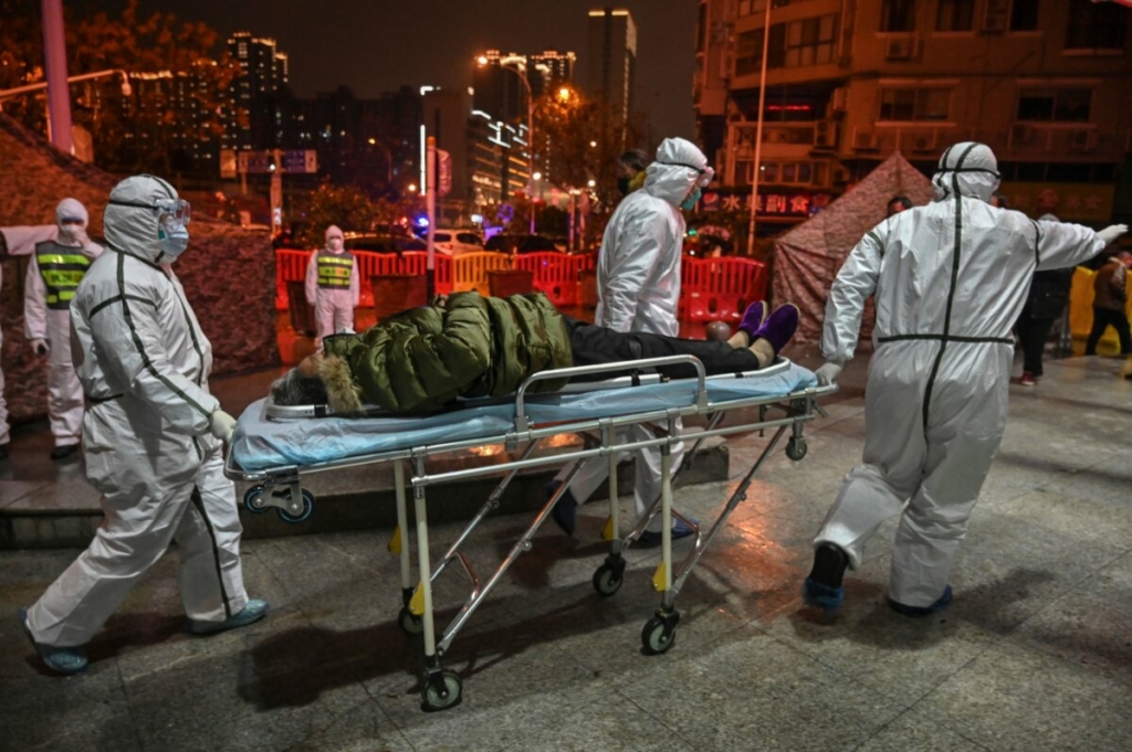 Nhân viên y tế mặc quần áo bảo hộ cùng một bệnh nhân đến Bệnh viện Hồng Thập Tự Vũ Hán ở Vũ Hán, tỉnh Hồ Bắc, Trung Quốc, vào ngày 25/01/2020. (Ảnh: Hector Retamal/AFP qua Getty Images)