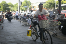 Một người đàn ông dắt xe đạp chở thùng dầu ăn rời siêu thị ở Bắc Kinh, hôm 12/06/2024. (Ảnh: Wang Zhao/AFP qua Getty Images)