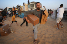 Người Palestine mang theo các thùng viện trợ nhân đạo sau khi lao tới các xe tải chở hàng viện trợ quốc tế từ Bến tàu Trident do Hoa Kỳ xây dựng gần Nuseirat ở miền trung Dải Gaza hôm 18/05/2024, trong bối cảnh xung đột đang diễn ra giữa Israel và nhóm quân sự Hamas. (Ảnh: AFP qua Getty Images)
