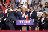 Cựu Tổng thống Donald Trump được dìu ra khỏi sân khấu tại một sự kiện tranh cử ở Butler, Pennsylvania, hôm 13/07/2024. (Ảnh: Gene J. Puskar/AP Photo)