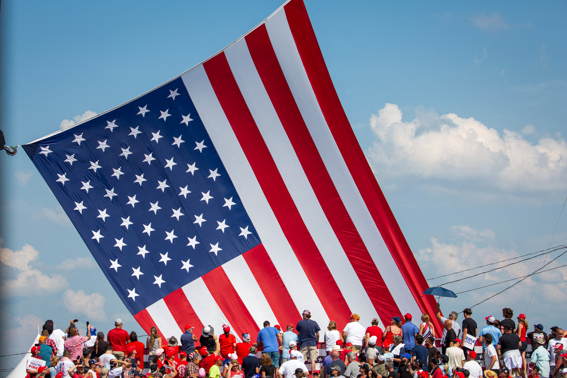 Mọi người nhìn về quốc kỳ Mỹ khi lá cờ được đặt vào vị trí tại sự kiện vận động tranh cử ở Butler, Pennsylvania, hôm 13/07/2024. (Ảnh: Rebecca Droke/AFP qua Getty Images)