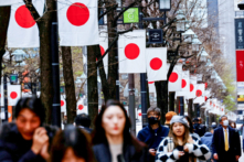 Người dân đi bộ ngang qua một hàng quốc kỳ Nhật Bản tại một khu mua sắm ở Tokyo hôm 19/03/2024. (Ảnh: Kim Kyung-Hoon/Reuters)