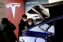 Du khách đeo khẩu trang xem mẫu xe thể thao đa dụng (SUV) Tesla Model Y do Trung Quốc sản xuất tại phòng trưng bày của hãng sản xuất xe điện này ở Bắc Kinh vào ngày 05/01/2021. (Ảnh: Tingshu Wang/Reuters)
